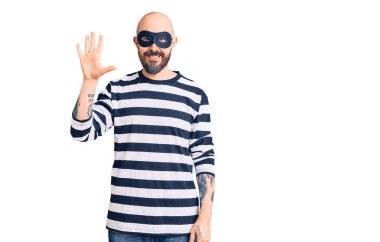 Hırsız maskesi takan genç yakışıklı beş numarayı gösterip işaret ederken kendinden emin ve mutlu bir şekilde gülümsüyor.. 