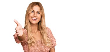 Yazlık bluz giyen güzel sarışın bir kadın gülümseyerek selamlama ve hoş geldin demek için tokalaşıyor. başarılı iş. 