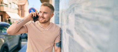 Genç İrlandalı gülümseyen mutlu bir adam şehrin caddesinde akıllı telefonda konuşuyor..