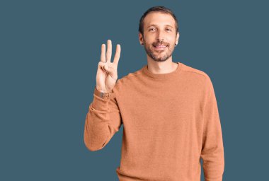 Gündelik kıyafetler giyen genç yakışıklı üç numarayı gösterip işaret ederken kendinden emin ve mutlu bir şekilde gülümsüyor.. 