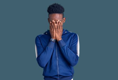 Genç Afro-Amerikan erkek spor giysisi giyiyor ve ağlarken yüzünü ellerle kapatıyor. depresyon kavramı. 