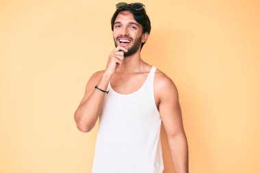 Yaz bakışı ve güneş gözlüğü takan yakışıklı İspanyol. Kameraya kendinden emin bakıyor. Kollarını kavuşturmuş ve çenesini kaldırmış gülümsüyor. Olumlu düşünmek. 