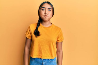 Gündelik kıyafetler giyen, komik yüzlü, yanak şişiren genç Latin kadın. Havayla şişmiş ağız, çılgın bir ifade.. 