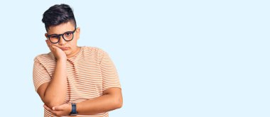 Günlük kıyafetler ve gözlük takan küçük çocuk kollarını kavuşturarak depresyon sorunlarından yorgun ve sıkılmış göründüğünü düşünüyor.. 