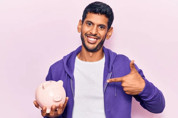 Jovem Latino Homem Segurando Porquinho Banco Apontando Dedo Para Auto — Fotografia de Stock