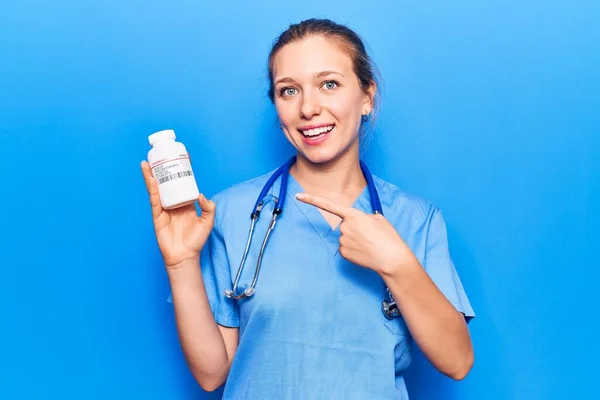 Jovem Bela Mulher Loira Vestindo Uniforme Médico Segurando Pílulas Sorrindo — Fotografia de Stock