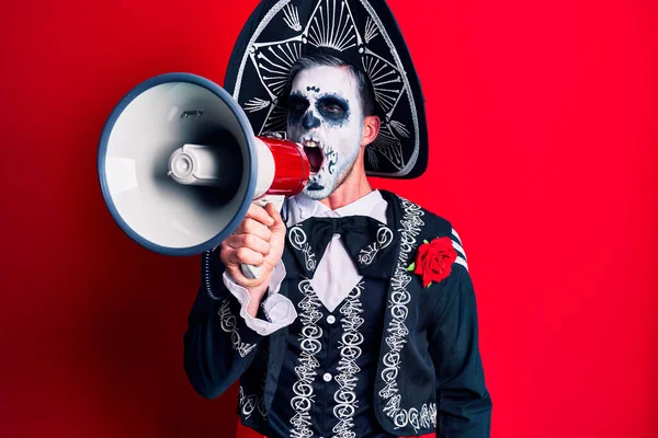 Scary man wearing day of the dead make up and costumbre from traditional ritual in Mexico shouting through megaphone