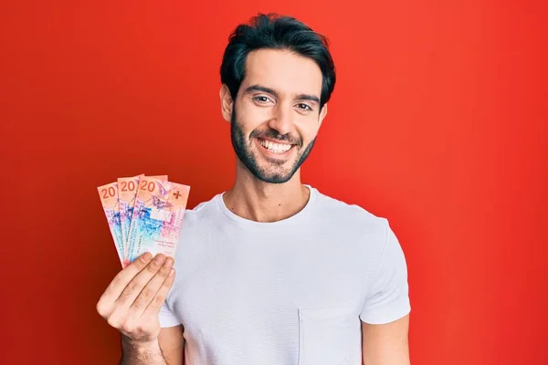 Ung Latinamerikansk Man Håller Schweiziska Franc Sedlar Ser Positiv Och — Stockfoto