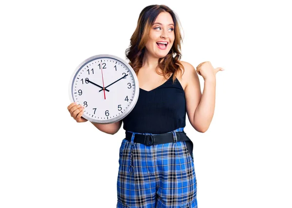 Young Beautiful Caucasian Woman Holding Big Clock Pointing Thumb Side — Stock Photo, Image