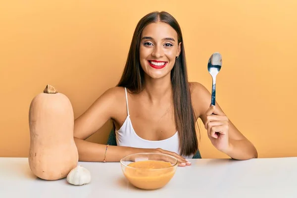 Junge Hispanische Frau Isst Kürbissuppe Mit Löffel Und Schaut Positiv — Stockfoto