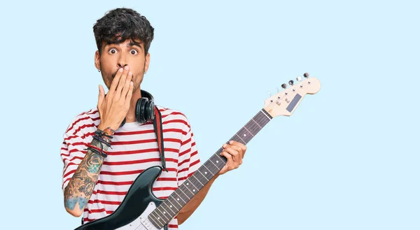 若いヒスパニック系の男性の手で口をカバーする電気ギターを演奏し ショックを受け ミスを恐れている 驚きの表情 — ストック写真