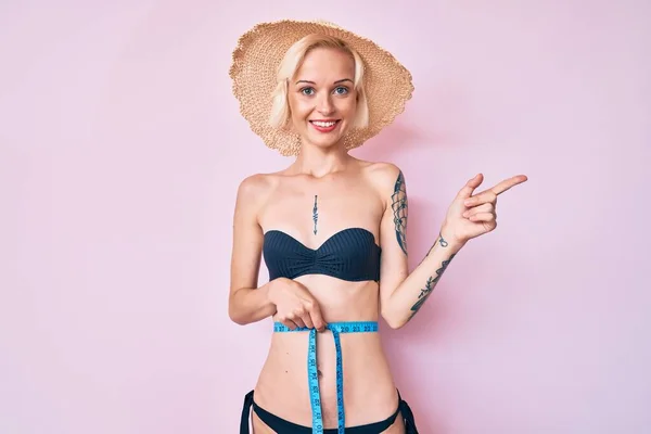 Młoda Blondynka Tatuażem Bikini Taśmą Mierzy Uśmiech Szczęśliwy Wskazując Ręką — Zdjęcie stockowe