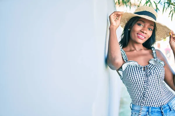 Young african american woman on vacation smiling happy leaning on the wall at street of city