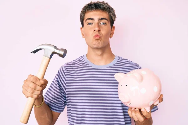 Jovem Homem Bonito Segurando Mealheiro Martelo Olhando Para Câmera Soprando — Fotografia de Stock