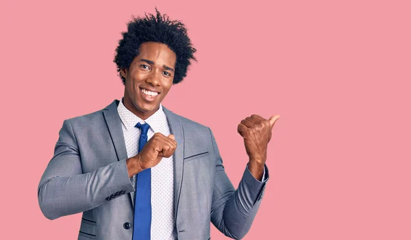 自信を笑顔 手と親指で後ろを指してビジネスジャケットを身に着けているアフロの髪を持つハンサムなアフリカ系アメリカ人男性 — ストック写真