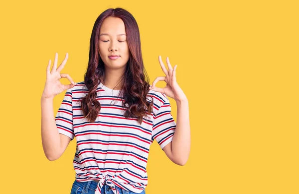 身穿休闲装的年轻漂亮的中国姑娘 闭上双眼 用手指做冥想手势 瑜伽概念 — 图库照片
