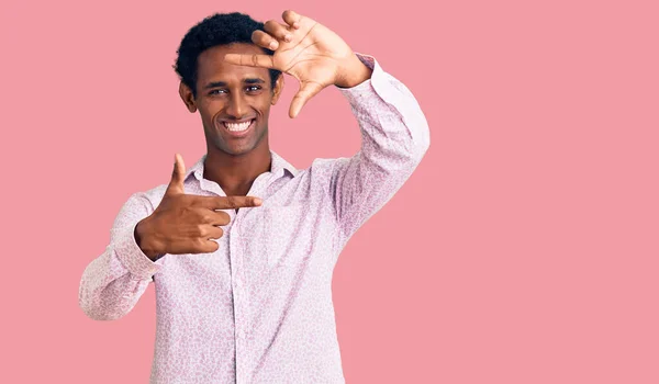 カジュアルなピンクのシャツを着たアフリカのハンサムな男が幸せな顔で手と指でフレームを作って笑っています 創造性と写真の概念 — ストック写真
