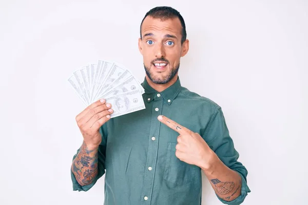 Joven Hombre Guapo Con Tatuaje Sosteniendo Dólares Sonriendo Feliz Señalando —  Fotos de Stock