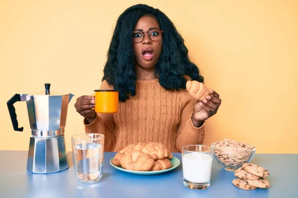 Jong Afrikaans Amerikaans Vrouw Eten Ontbijt Houden Croissant Shock Gezicht — Stockfoto
