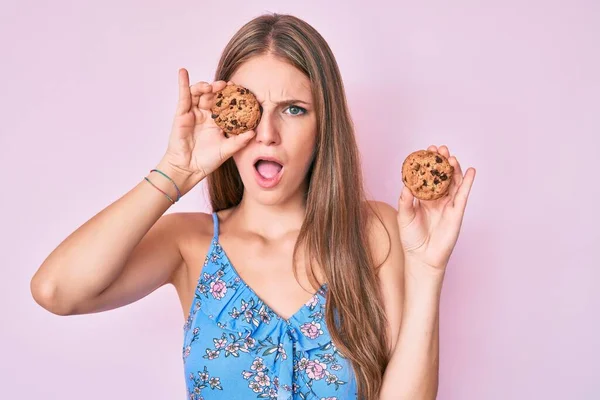 Young Blonde Girl Holding Cookie Shock Face Looking Skeptical Sarcastic — Stock Photo, Image
