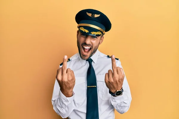 Handsome Hispanic Man Wearing Airplane Pilot Uniform Showing Middle Finger — Stockfoto