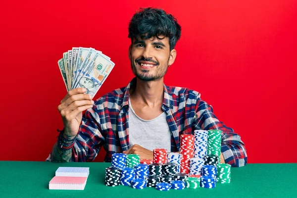 Joven Hombre Hispano Sentado Mesa Con Fichas Póquer Cartas Sosteniendo —  Fotos de Stock