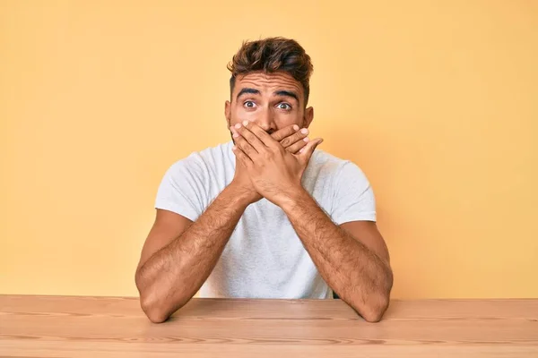 Jovem Hispânico Vestindo Roupas Casuais Sentado Mesa Chocou Cobrindo Boca — Fotografia de Stock