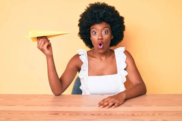 Young African American Woman Holding Paper Airplane Scared Amazed Open — Stock Photo, Image