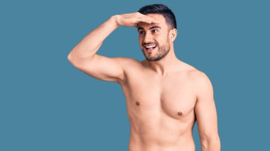 Mayo giyen genç ve yakışıklı bir adam çok mutlu ve gülümseyerek başını kaldırmış uzaklara bakıyor. arama kavramı. 