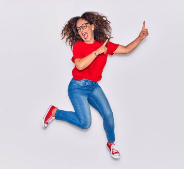 Orta yaşlı, güzel İspanyol bir kadın günlük kıyafetler ve mutlu bir gülümseme takınıyor. İzole edilmiş beyaz arka planda yüzünde gülümsemeyle zıpla