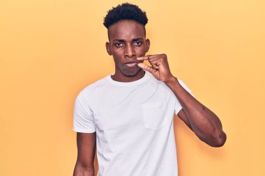 Sıradan kıyafetler giyen, ağzı ve dudakları parmaklarıyla kapanmış genç Afro-Amerikan bir adam. gizli ve sessiz, tabu konuşması 