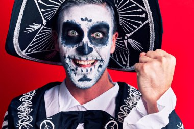 Kırmızı arka planda Meksika kostümlü genç adam gururla bağırıyor zaferi ve başarıyı kollarını kaldırarak kutluyor. 