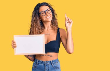 Elinde boş beyaz karatahta olan Latin kökenli genç bir kadın bir fikir ya da soruyla şaşırdı ve mutlu yüzle işaret etti. 