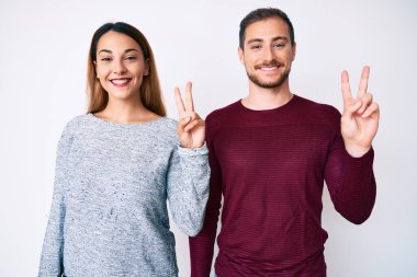 Güzel bir çift günlük kıyafetler giyip gülümsüyor ve kameraya göz kırpıyor. Zafer işareti yapıyorlar. İki numara.. 