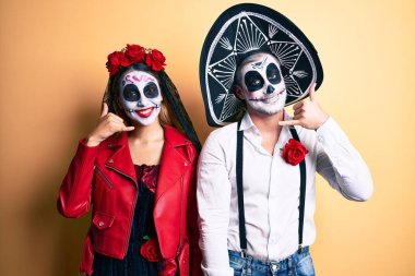 Ölü kostümün giyildiği gün sarıya gülümseyen bir çift telefonda konuşur gibi el ve parmaklarıyla telefon hareketi yapıyor. iletişim kavramları. 