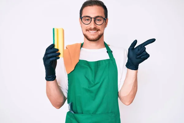 Joven Hombre Guapo Usando Delantal Sosteniendo Scourer Sonriendo Feliz Señalando — Foto de Stock