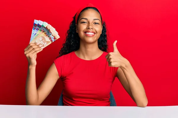 Jovem Afro Americana Segurando Dólares Canadenses Sentado Mesa Sorrindo Feliz — Fotografia de Stock