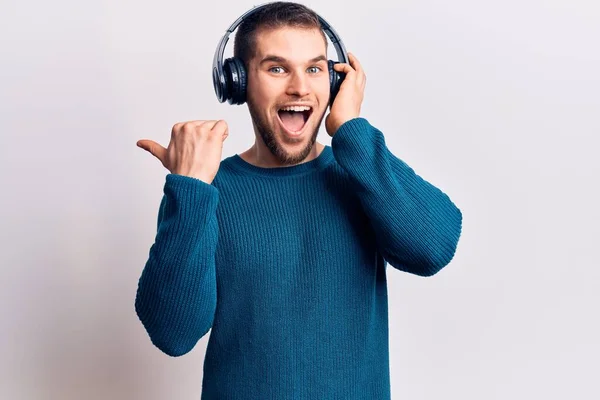 Mladý Pohledný Muž Který Poslouchá Hudbu Pomocí Sluchátek Ukazujících Palcem — Stock fotografie