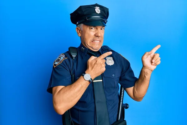 Handsome middle age mature man wearing police uniform pointing aside worried and nervous with both hands, concerned and surprised expression