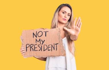 Genç, güzel, sarışın bir kadın, elinde benim başkanlık karton pankartımla değil, dur işareti yapıyor, ciddi ve kendinden emin bir ifadeyle, savunma jesti yapıyor. 