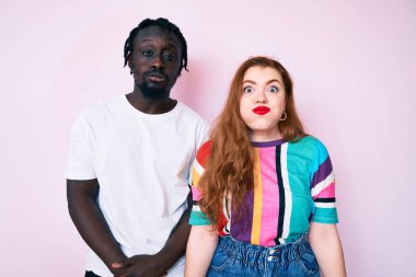 Sıradan kıyafetler giyen, komik yüzlü, yanak şişiren ırklar arası bir çift. Havayla şişmiş ağız, çılgın bir ifade.. 