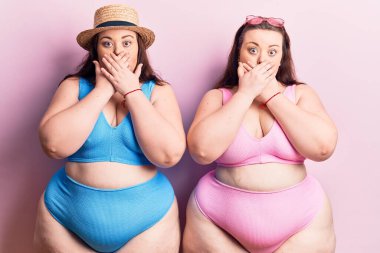 Bikini giyen genç ve büyük beden ikizler yanlışlıkla ağızlarını kapatarak şok oldular. gizli kavram. 