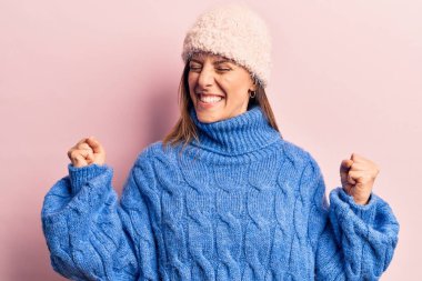 Kışlık giysiler giyen çok mutlu ve heyecanlı genç bir kadın kollarını kaldırıp, gülümseyerek ve başarı için çığlık atarak zafer jesti yapıyor. kutlama konsepti. 