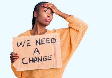 Elinde bir değişiklik pankartı tutan Afro-Amerikalı genç bir kadın var. Başı dönük, şaşırmış ve kızgın bir yüzü var. 
