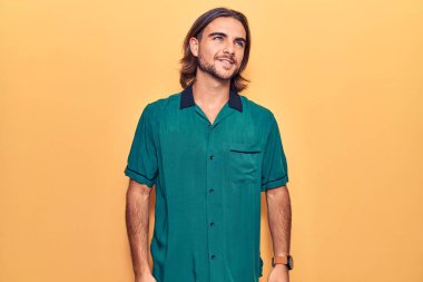 Sıradan kıyafetler giyen, rahat bir görünüm takınan, doğal yüzlü ve kendine güvenen genç yakışıklı bir adam.. 