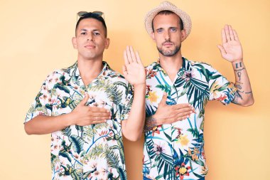 Genç eşcinsel iki adam yaz şapkası ve Hawaii gömleği giyip el pençe divan yemin ederek sadakat yemini ediyorlar. 