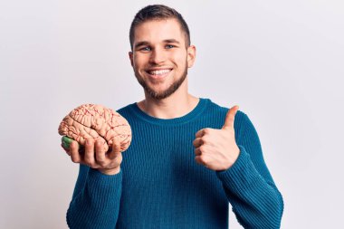 Beyni gülen, mutlu ve olumlu gülümseyen, mükemmel ve onay işareti yapan genç yakışıklı bir adam. 