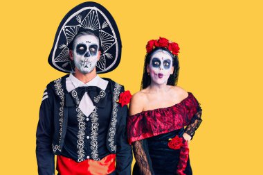 Arka planda Meksika tarzı ölü kostümler giyen genç bir çift dudakları olan balık suratlı, çılgın ve komik bir jest yapıyor. Komik ifade. 