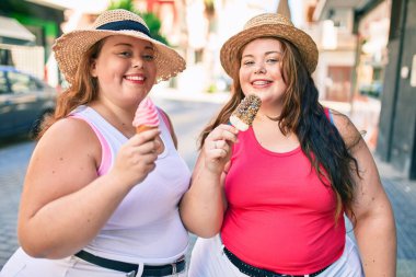 İki tane kilolu abla ikiz kız kardeş dışarıda dondurma yerken gülümseyen kadınlar.