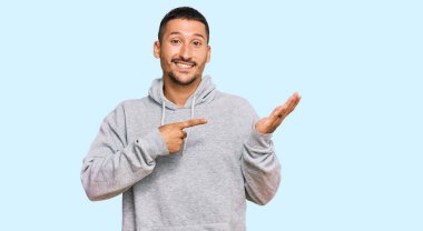 Sıradan bir kazak giyen yakışıklı bir adam kameraya hayret ediyor ve gülümsüyor.. 